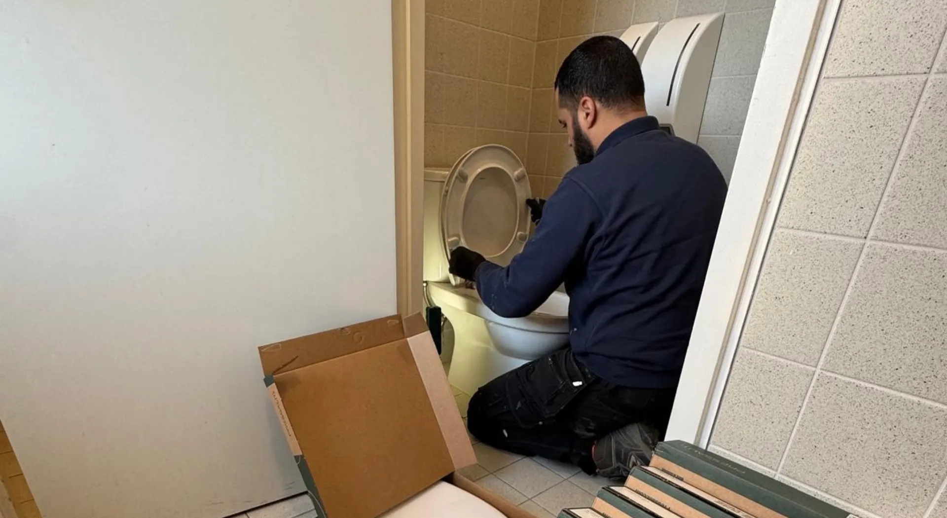 Loodgieter plaatst of vervangt een wc-bril tijdens onderhoud aan een toilet.